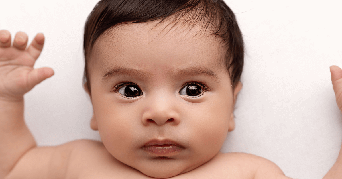 A close-up photo of a baby with their arms up